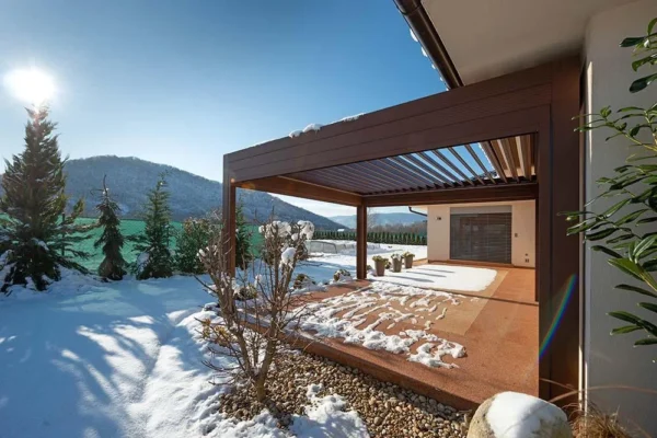 Moderne Terrasse mit brauner Pergola im verschneiten Hof - perfekt für Wintervorbereitung und gemütliche Tage.