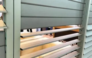 Weiße Jalousien mit einer verbogenen Lamelle, die eine Lücke in der Reihe verursacht.